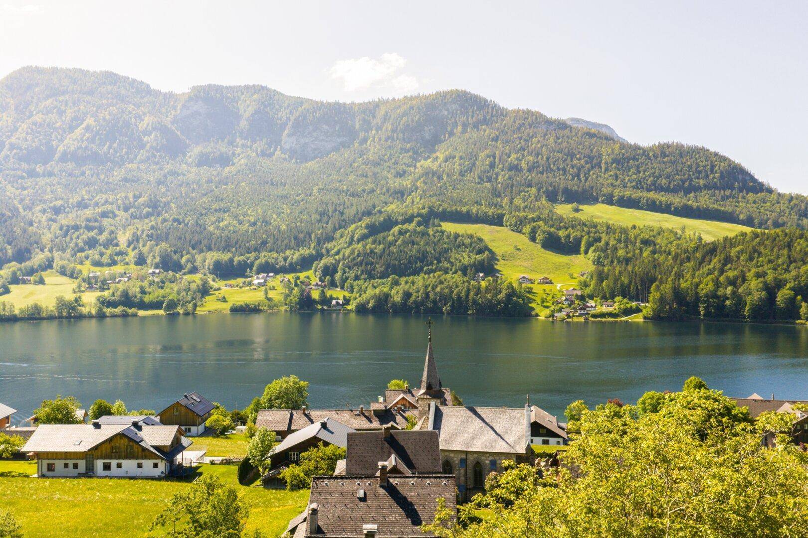 Malerischer Blick auf den See und die umliegenden Berge mit traditionellen Häusern.