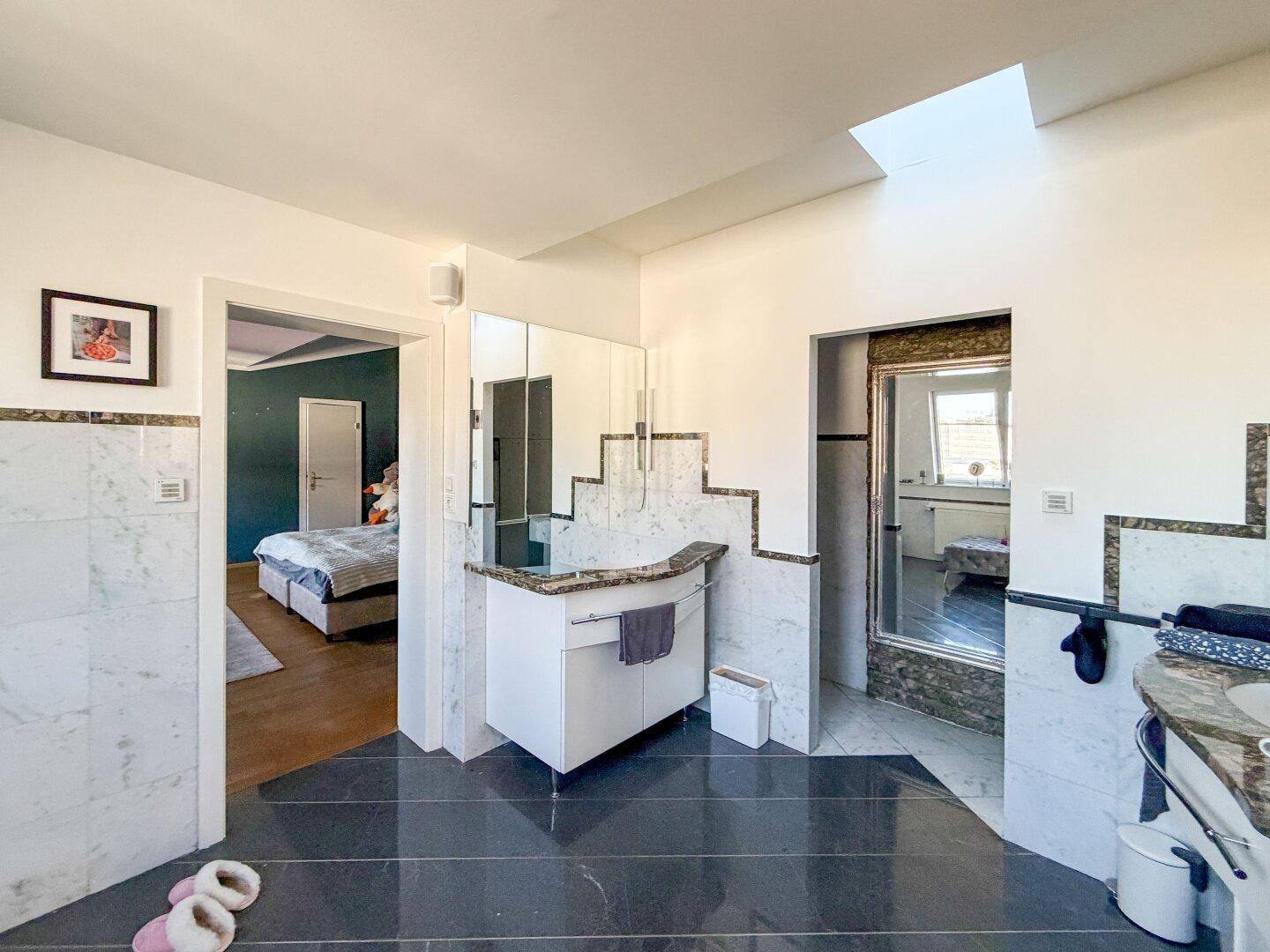 Modernes Badezimmer mit Waschtisch, Spiegel und direktem Zugang zum Schlafzimmer.