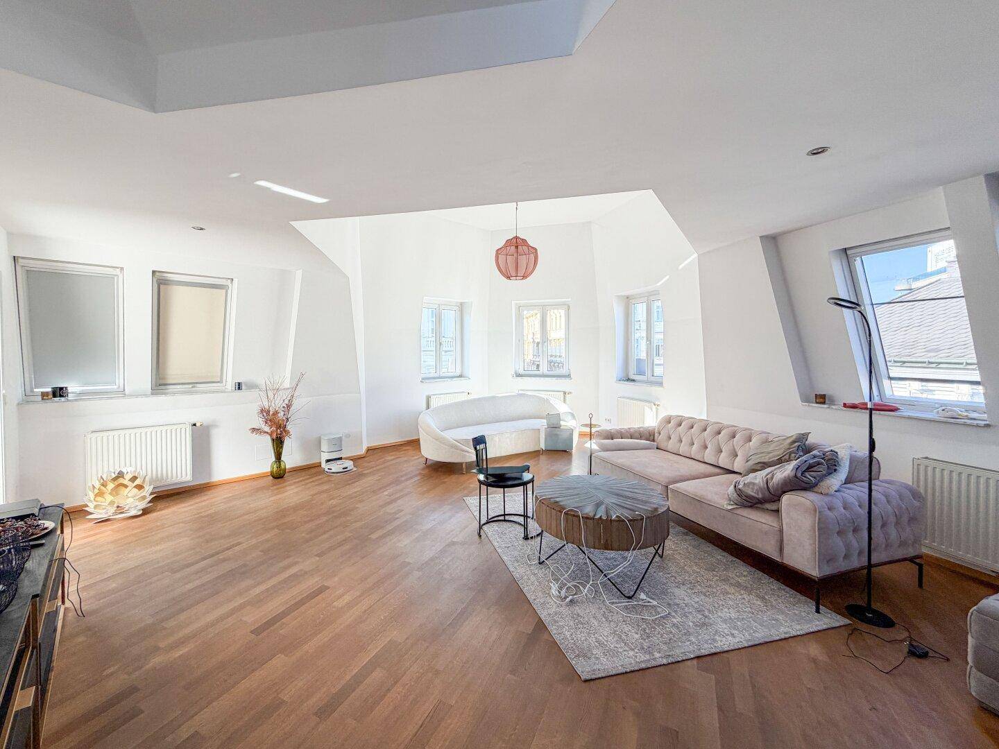 Lichtdurchflutetes Wohnzimmer mit Dachschrägen, Holzboden und gemütlicher Sitzecke für Entspannung.