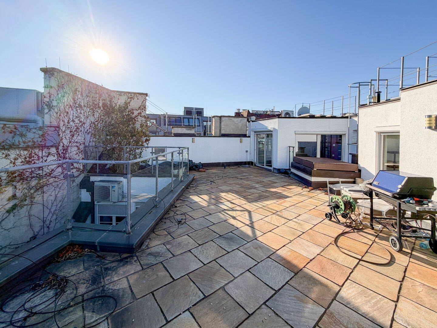 Weitläufige Dachterrasse mit Fliesenboden, Grillbereich und sonnigem Ambiente für Entspannung.