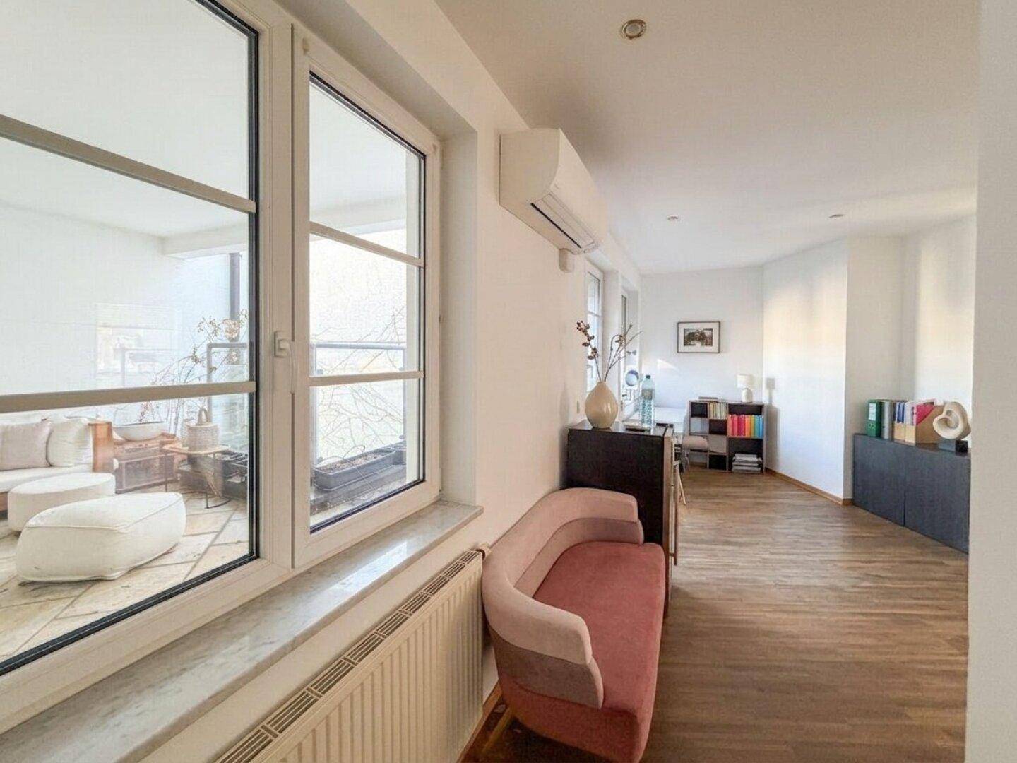 Heller Bürobereich mit Holzboden, Klimaanlage und Blick nach draußen durch das Fenster.
