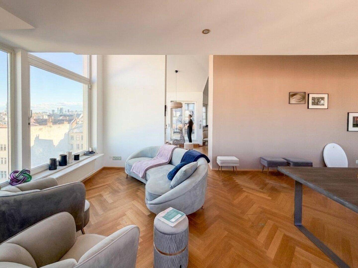 Gemütliches Wohnzimmer mit geschwungenem Sofa, großen Fenstern und weitem Ausblick.