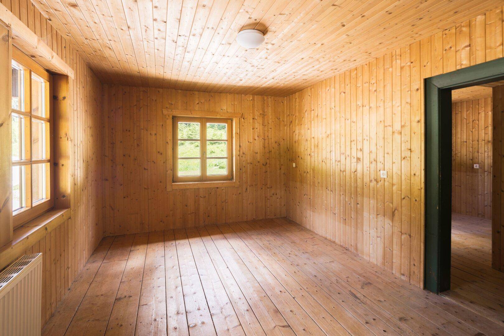 Gemütliches Zimmer mit Holztäfelung an Wänden und Decke sowie Holzdielenboden.