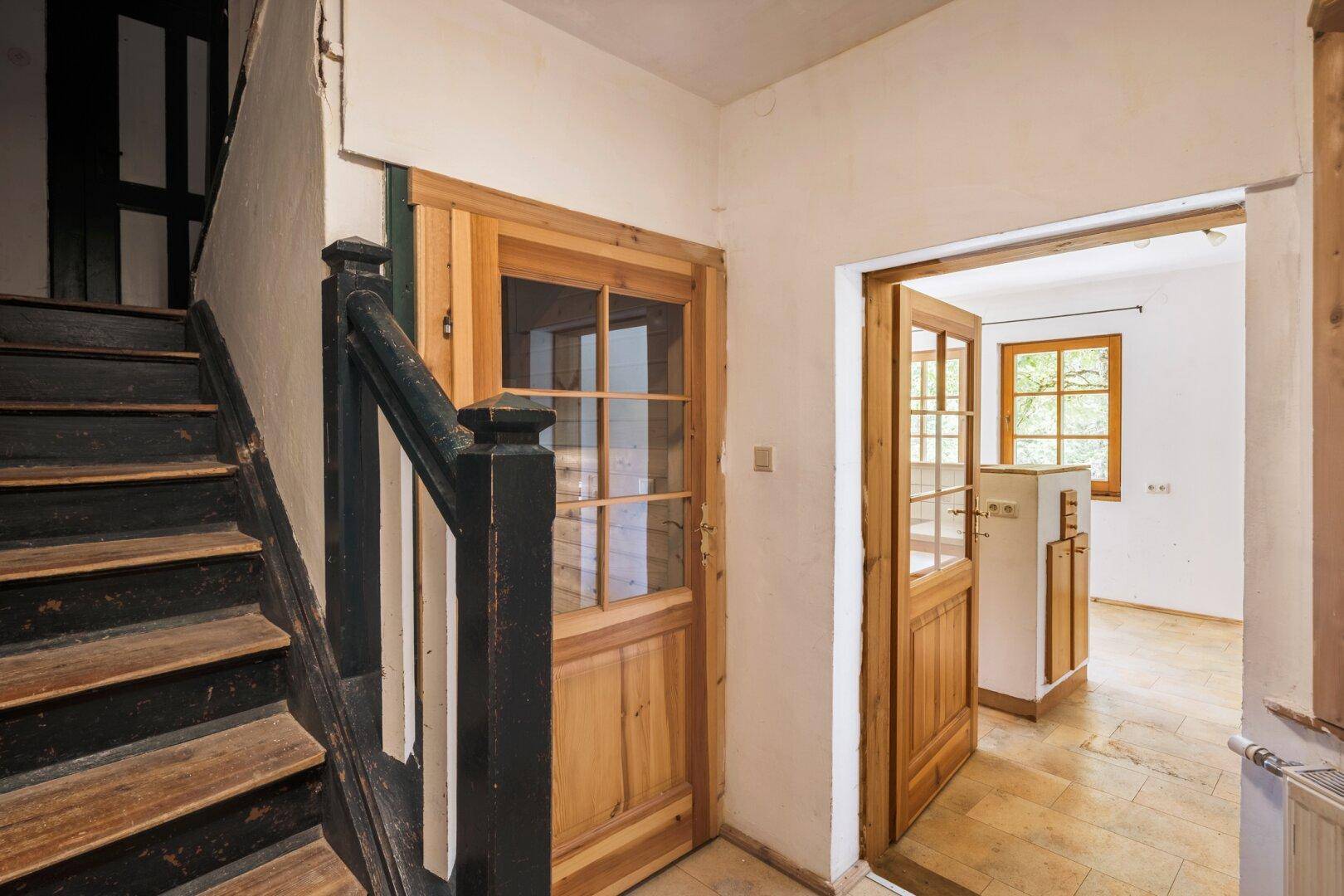 Flur mit rustikaler Holztreppe und Zugang zu weiteren Räumen im Erdgeschoss.