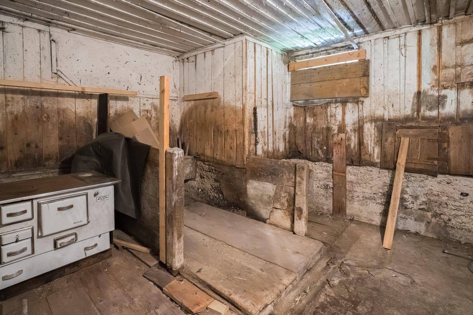 Rustikaler Abstellraum mit Holzwänden, alten Dielen und einem Holzofen.