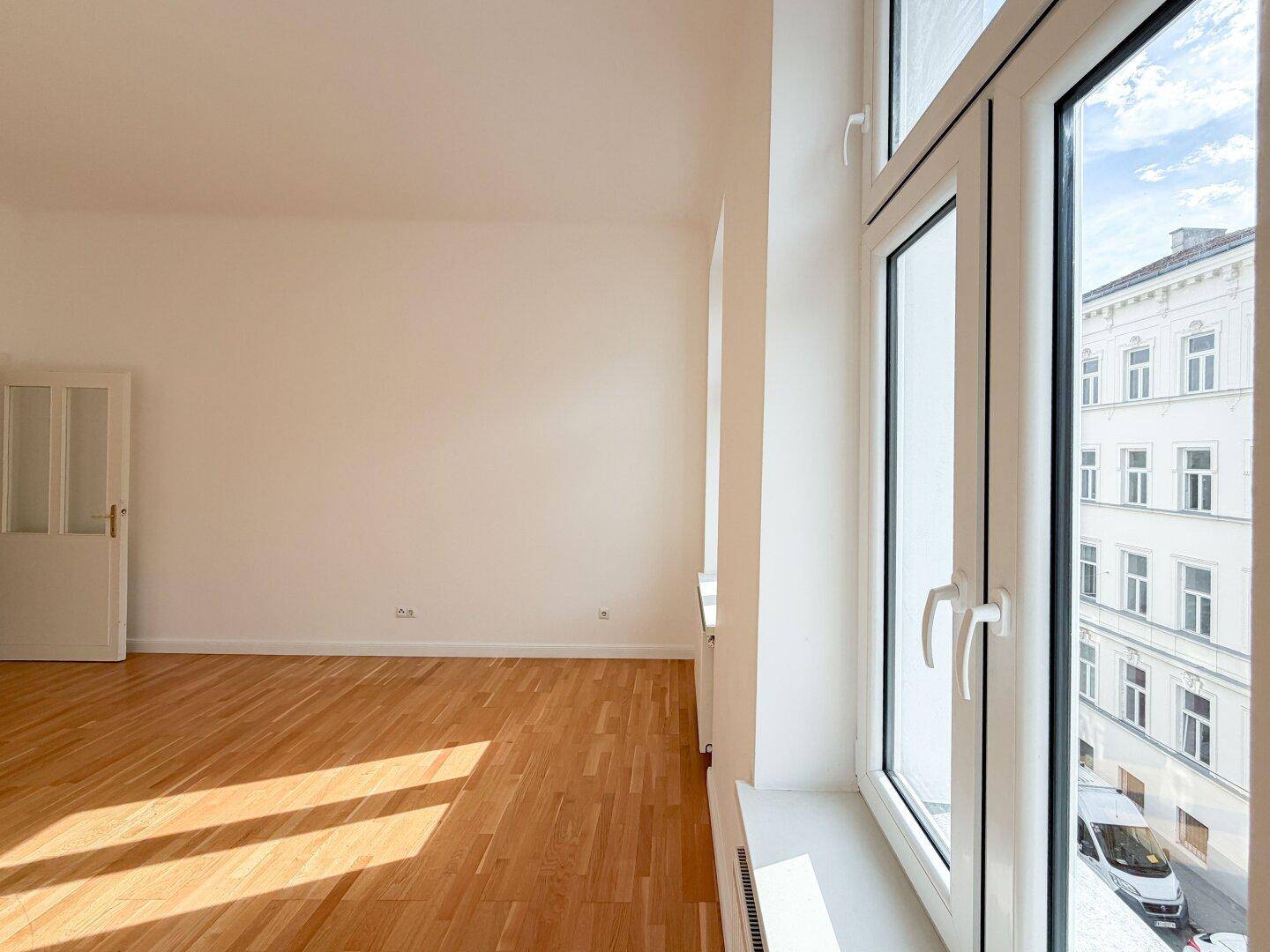 Blick aus dem Wohnzimmerfenster auf die gegenüberliegende historische Fassade und die Straße.