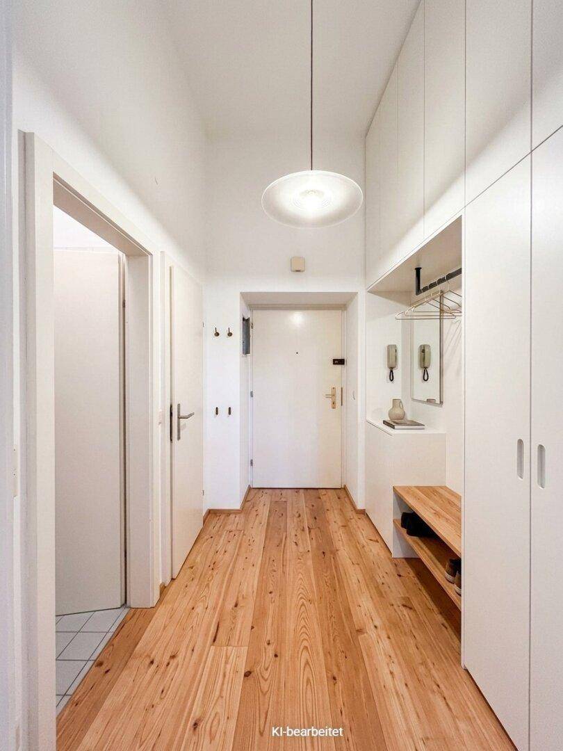Heller Flur mit Holzdielenboden, Einbauschränken und Garderobe.