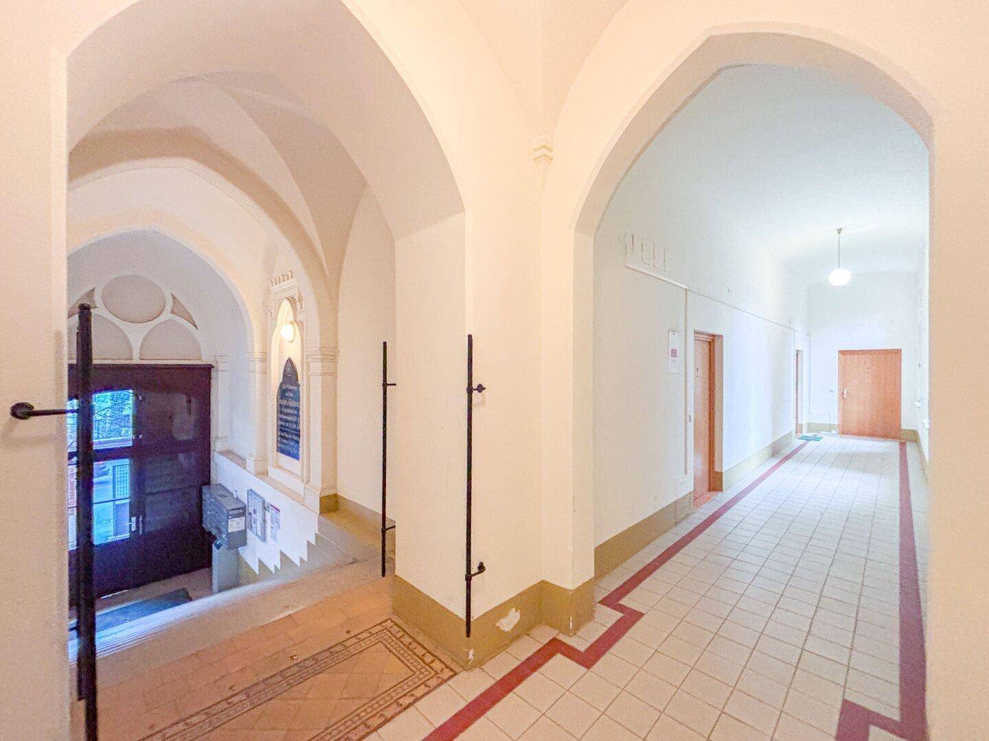 Historischer Flur mit Gewölbebögen, Fliesenboden und Zugang zu den Wohnungen.