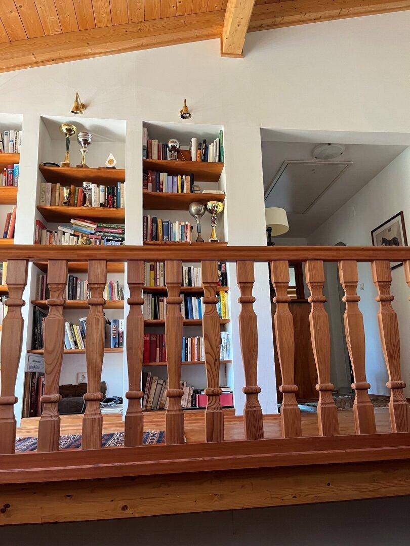 Galeriebereich mit eingebauten Bücherregalen und einer Holzbalustrade.