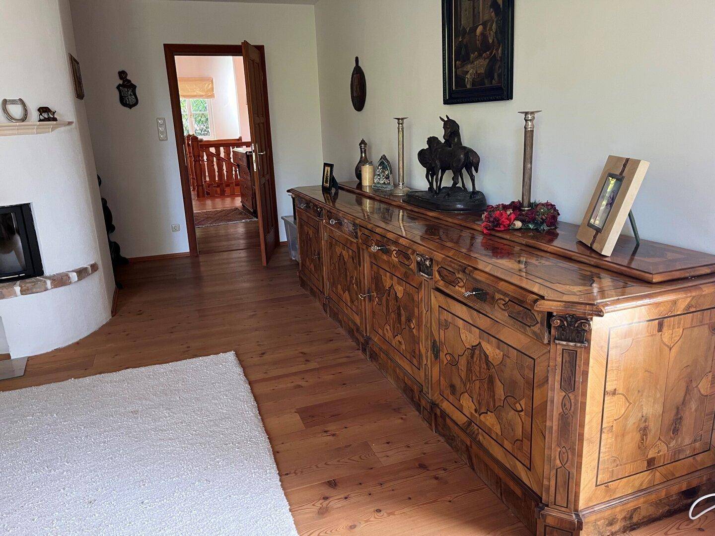 Geräumiger Flur mit antikem Holzschrank, Kamin und Holzboden.