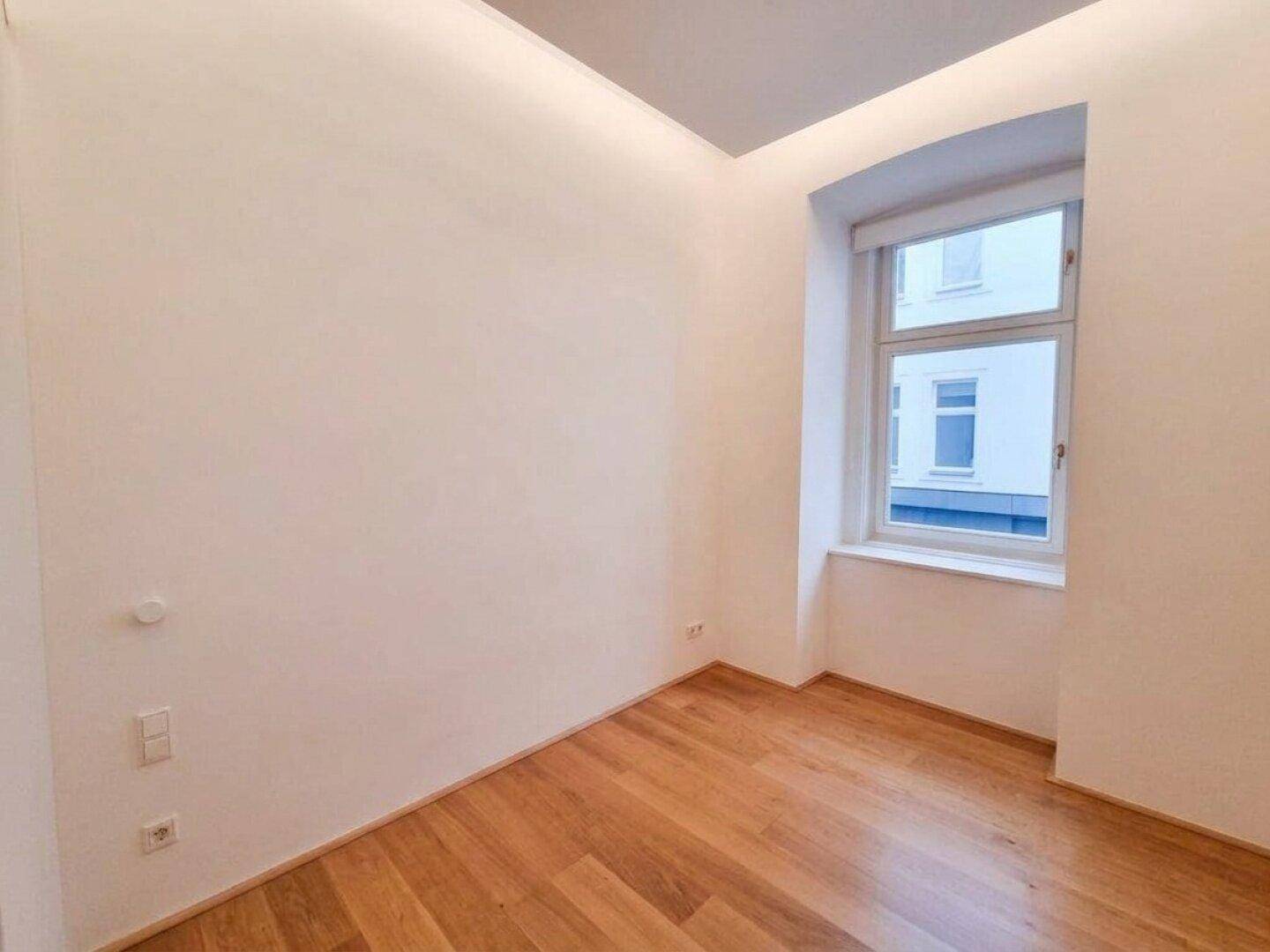 Heller Raum mit Holzboden und großem Fenster, ideal als Schlafzimmer oder Arbeitszimmer nutzbar.