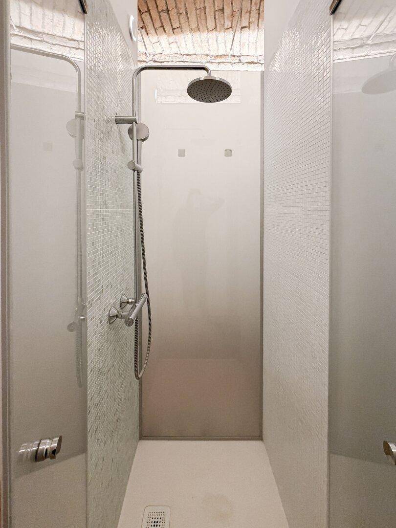 Moderne Duschkabine mit Regendusche und eleganten Mosaikfliesen an den Wänden.