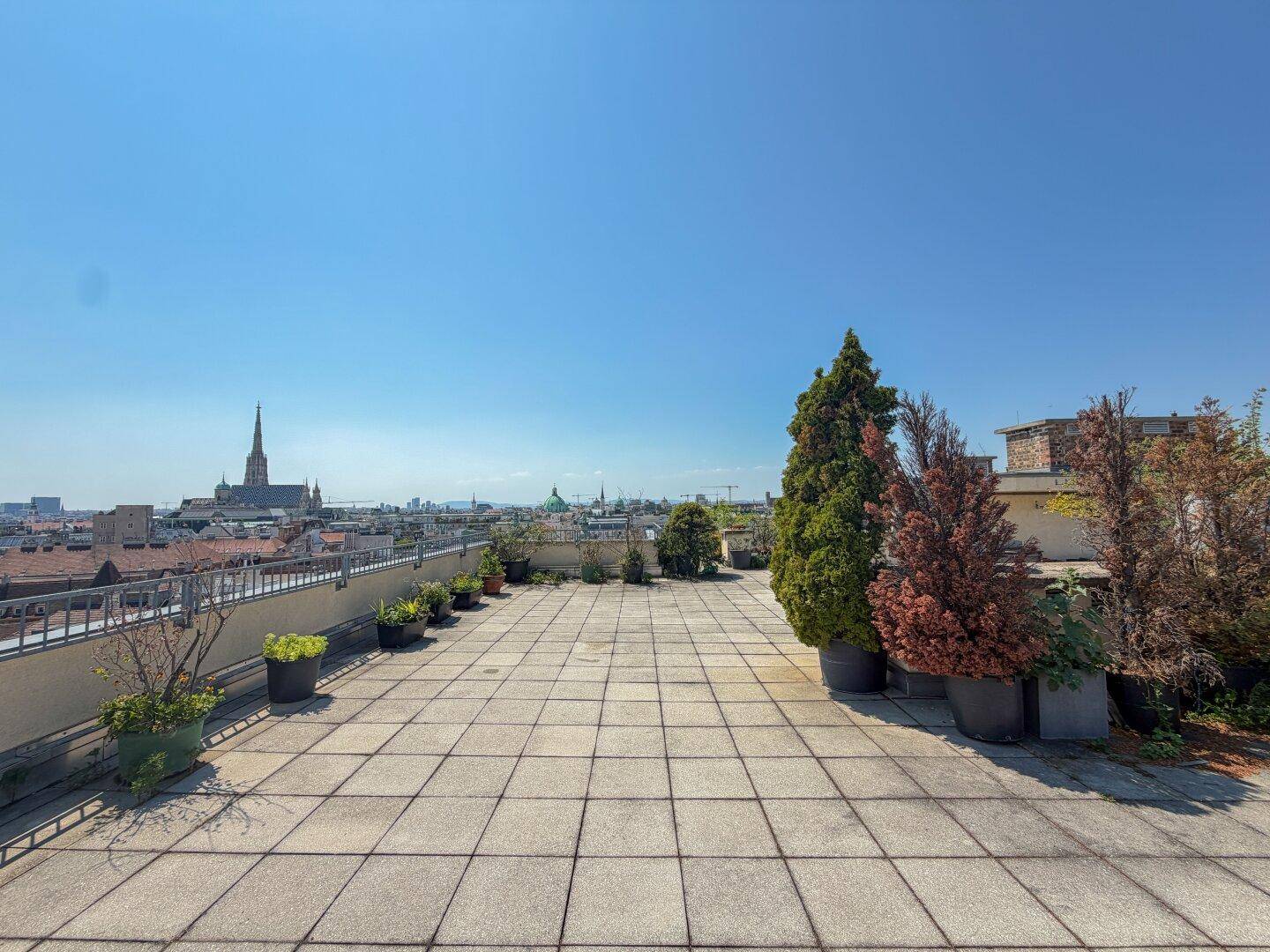Weitläufige Dachterrasse mit Fliesenboden und Topfpflanzen, ideal für Entspannung über den Dächern der Stadt.