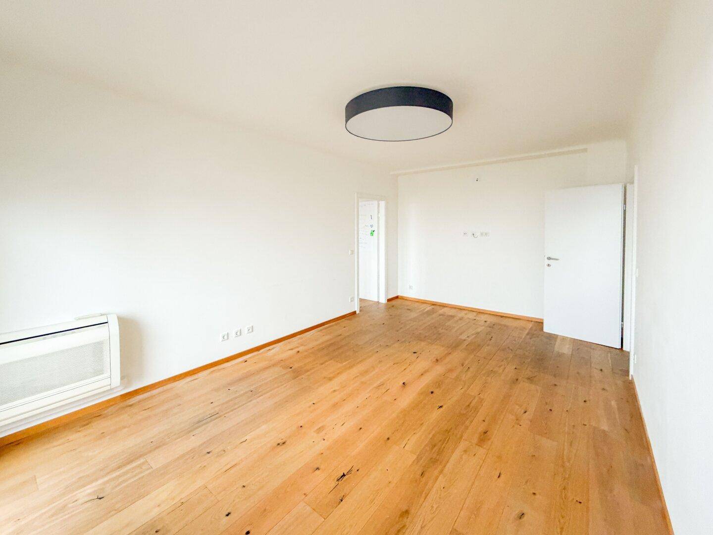 Geräumiges, helles Zimmer mit Holzparkettboden und weißen Wänden, bereit zur individuellen Gestaltung.