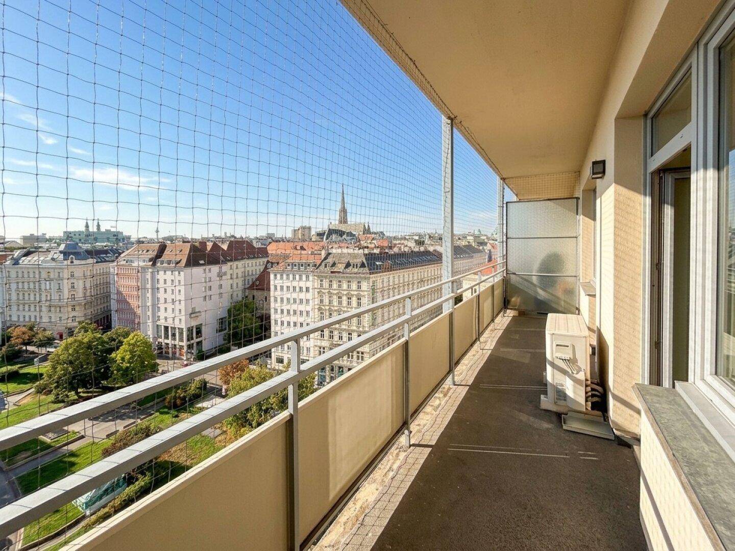 Balkon mit Sicherheitsnetz und schöner Aussicht auf die Stadt und grüne Parkanlagen.