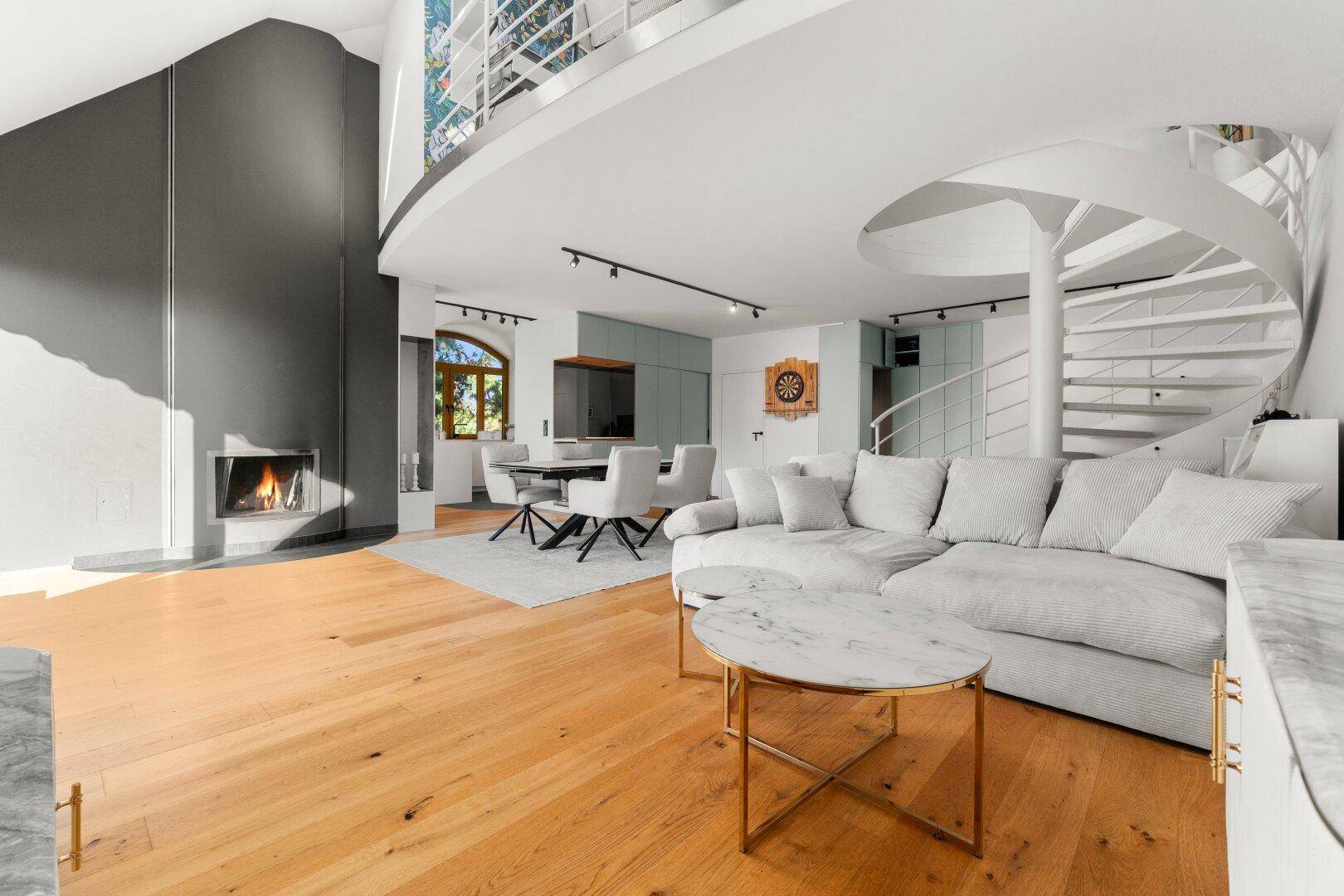 Großzügiger offener Wohnbereich mit Kamin, Wendeltreppe und Blick auf die obere Etage.