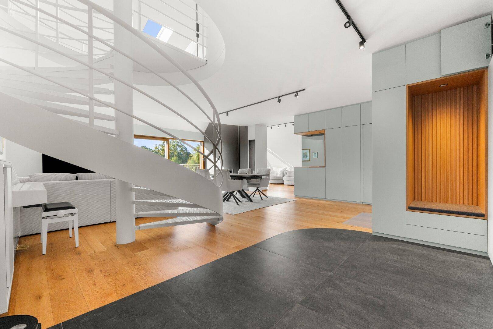 Eingangsbereich mit moderner Wendeltreppe, integrierten Schränken und Übergang zum Wohnbereich.