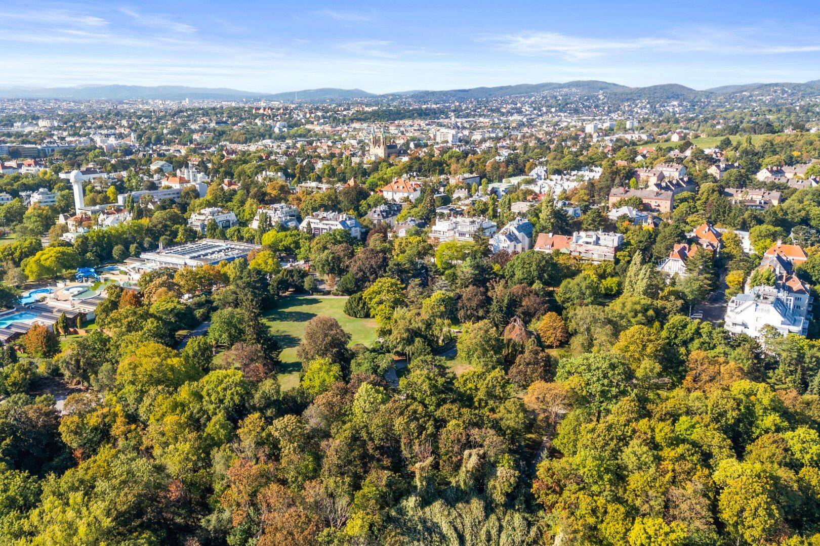 Panoramablick aus der Vogelperspektive über eine grüne Stadtlandschaft mit vielen Bäumen.