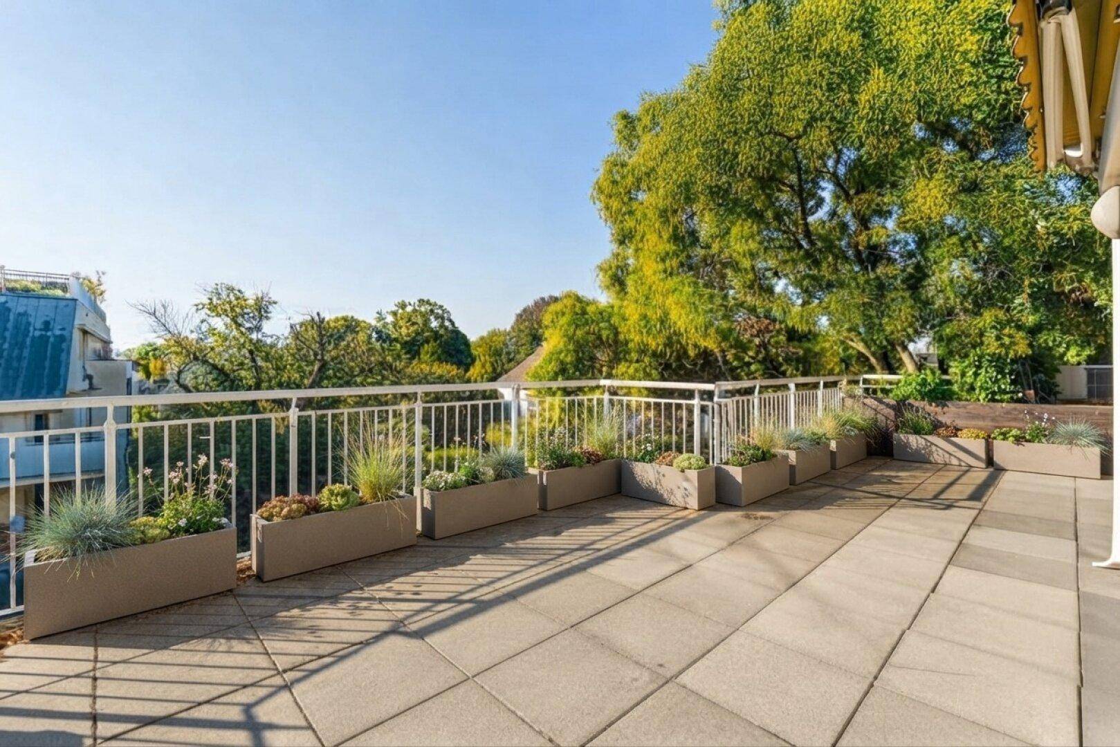 Geräumige Terrasse mit Fliesenboden, Pflanzenkübeln und weitem Blick ins Grüne.
