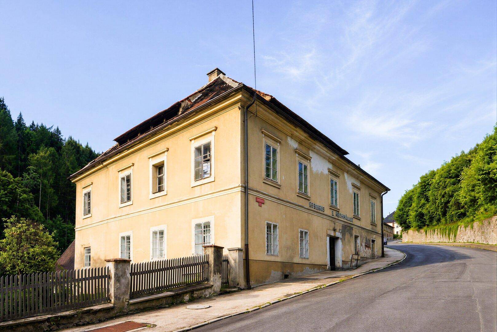 Historisches Gebäude mit gelber Fassade und traditionellen Fenstern an einer Straße gelegen.