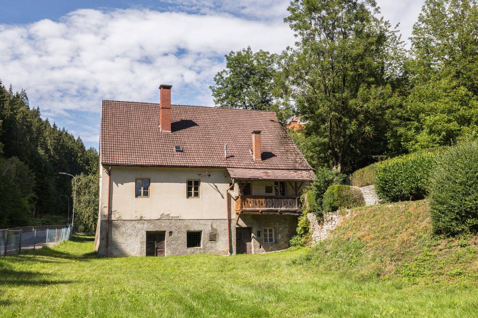 Kleineres Nebengebäude mit Balkon und großem Gartenbereich, umgeben von viel Grün.