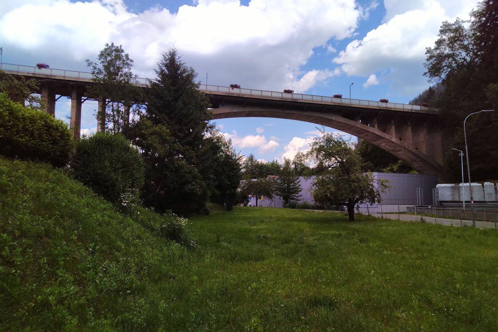 Malerische Brücke über ein Tal, umgeben von üppiger grüner Landschaft und Wald.