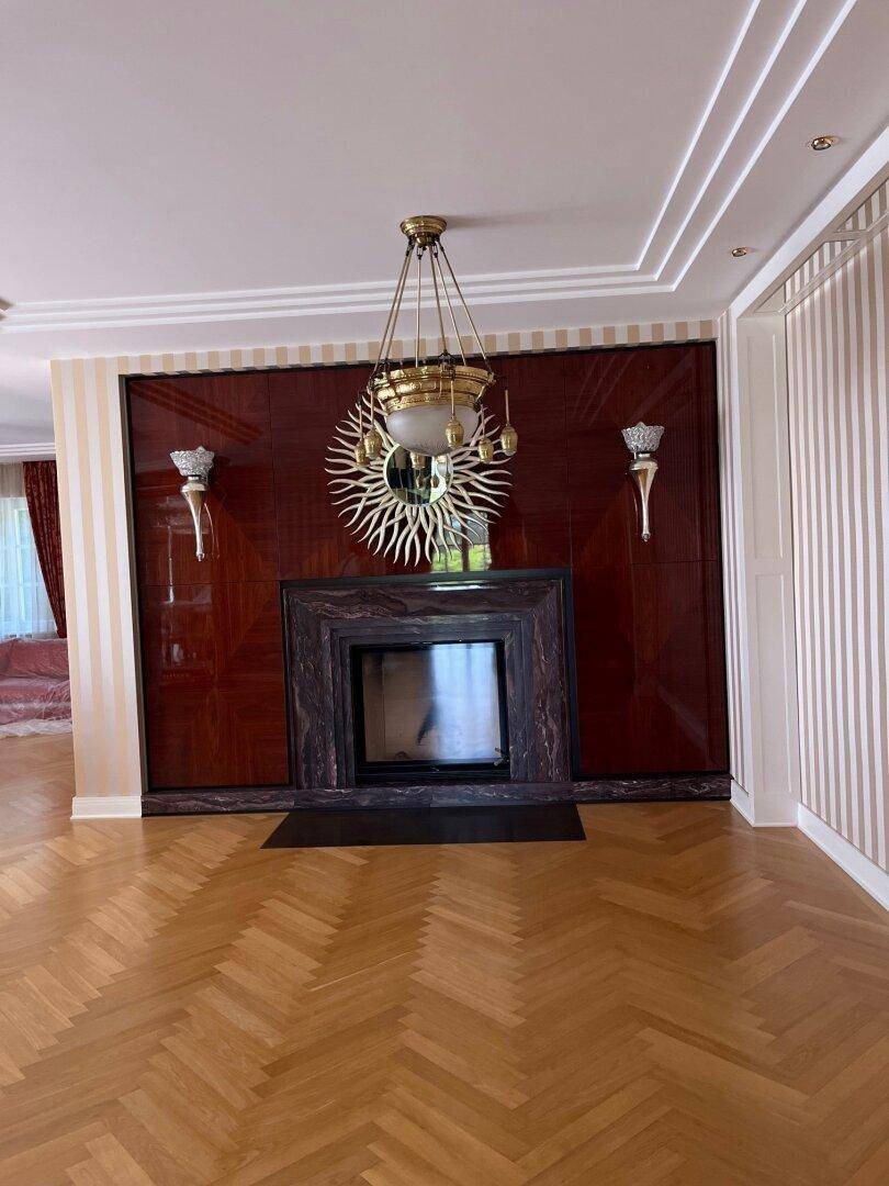 Elegantes Wohnzimmer mit Fischgrätparkett, Marmorkamin und dekorativer Wandgestaltung.