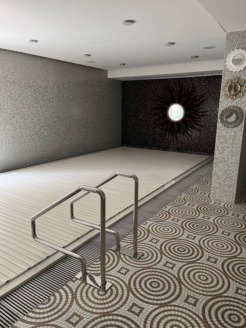 Innenpoolbereich mit Mosaikfliesen, Abdeckung und stilvoller Wanddekoration.