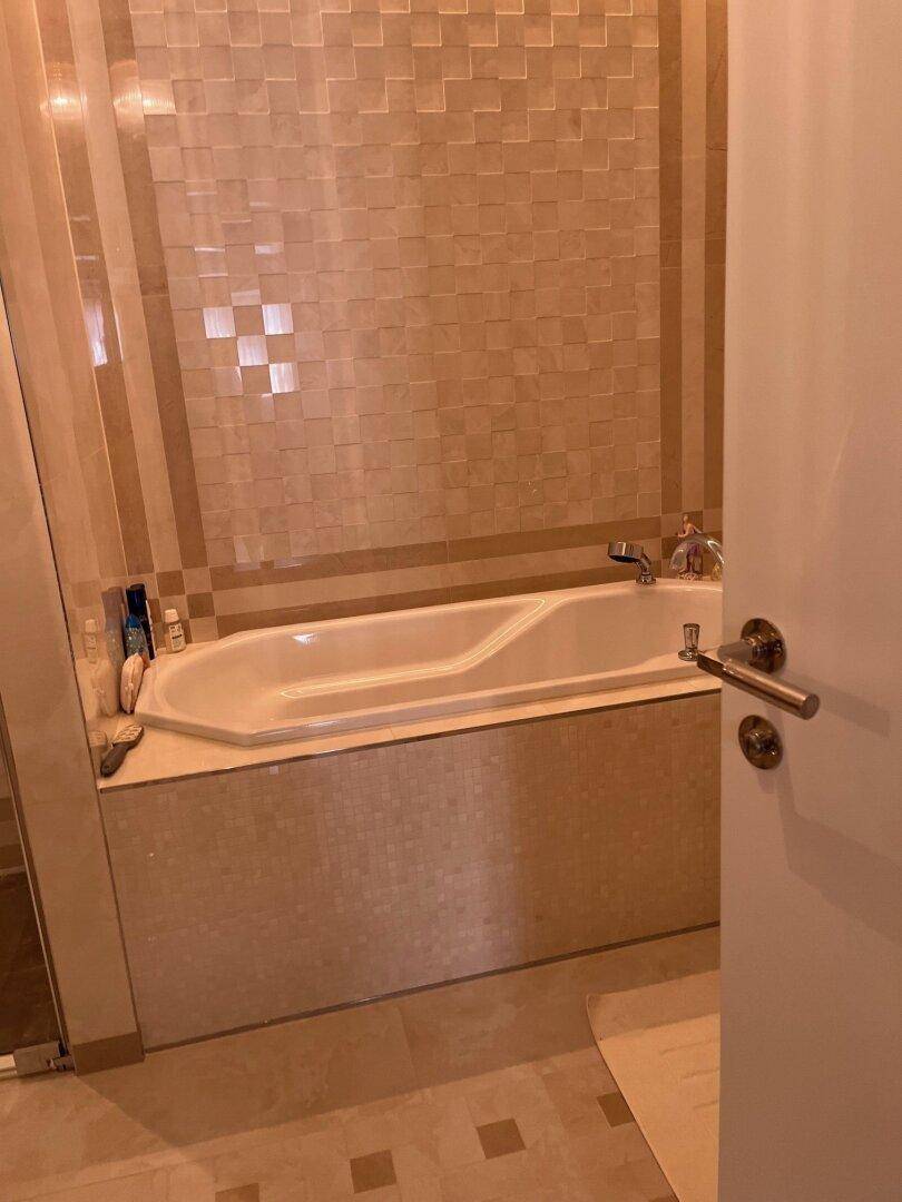 Helles Badezimmer mit eingebauter Badewanne und beigefarbenen Wandfliesen.