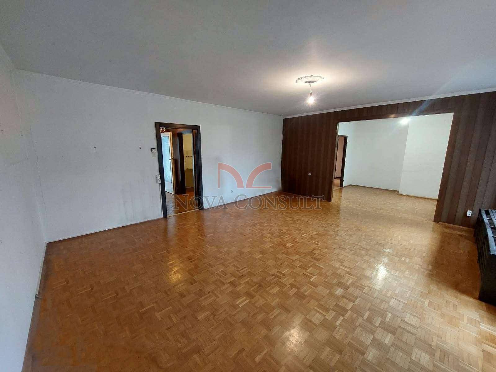 Helles Wohnzimmer mit Parkettboden und Zugang zu einem weiteren Raum.