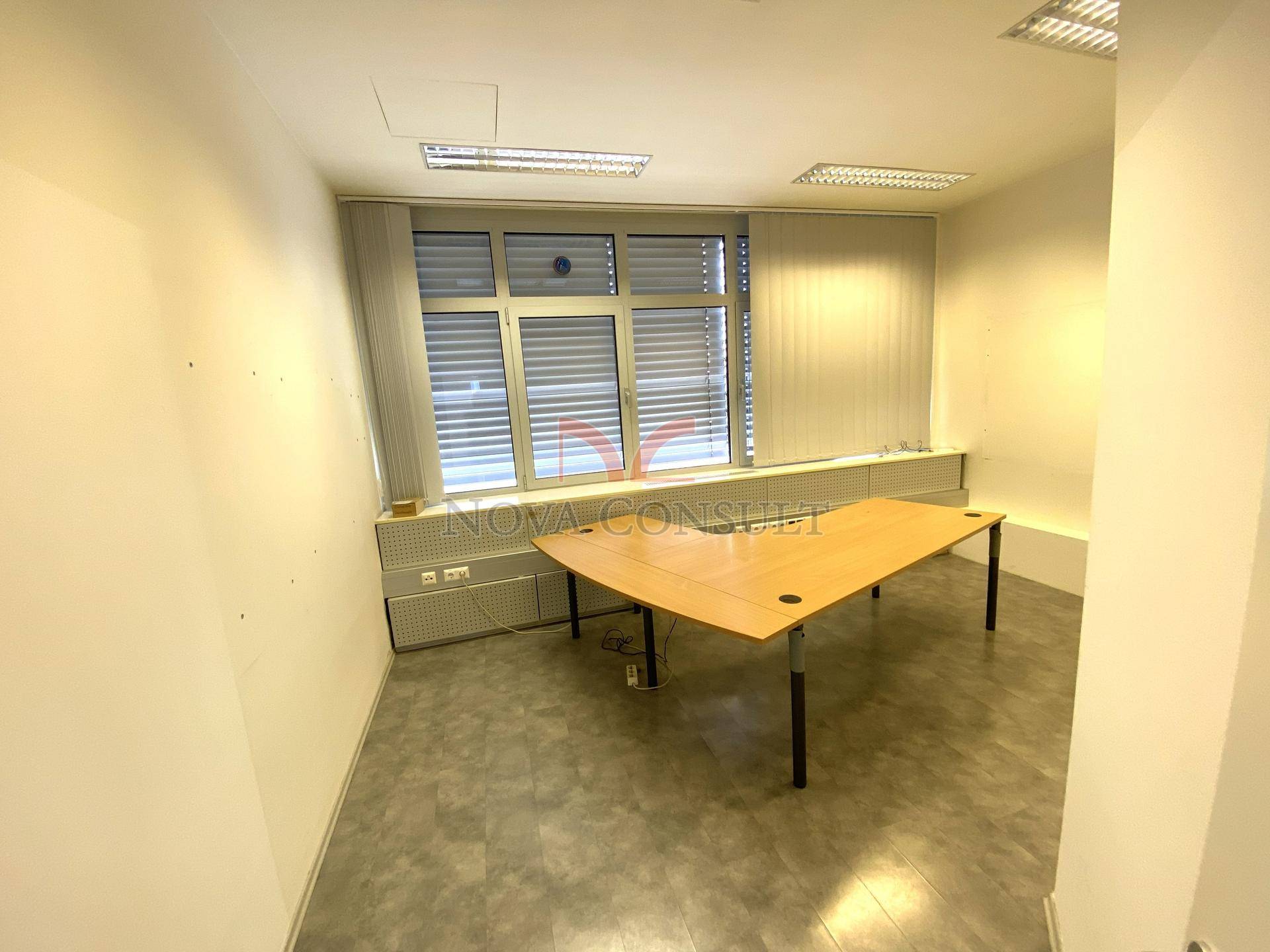 Leeres Bürozimmer mit einem Eckschreibtisch und einem Fenster für natürliche Belichtung.