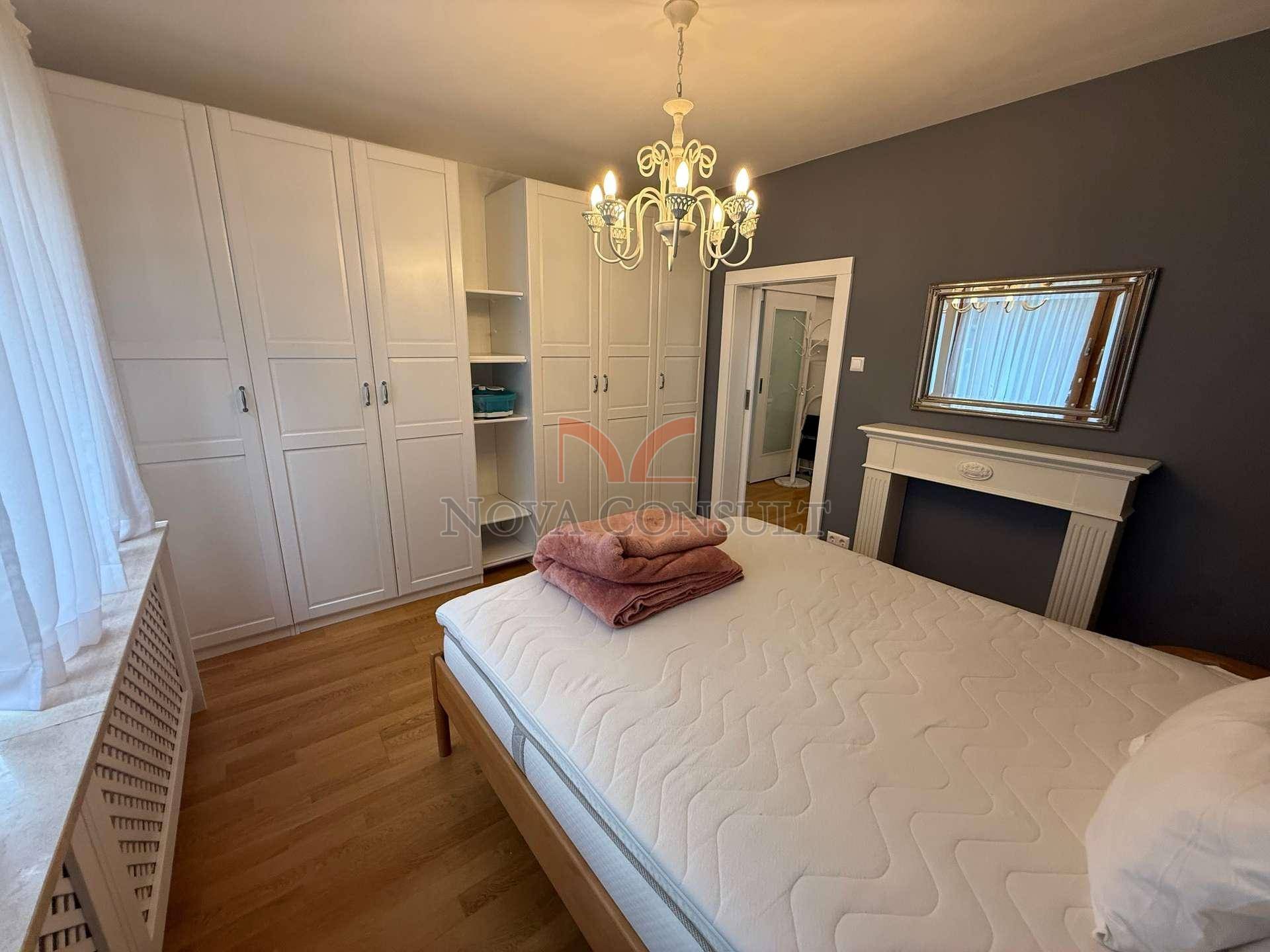 Schlafzimmer mit Einbauschränken, Parkettboden und dekorativem Spiegel über dem Bett.