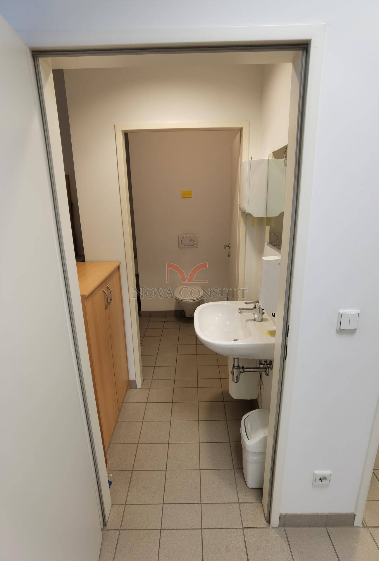 Toilettenraum mit Waschbecken und WC, ausgestattet mit Fliesenboden und einem kleinen Schrank.