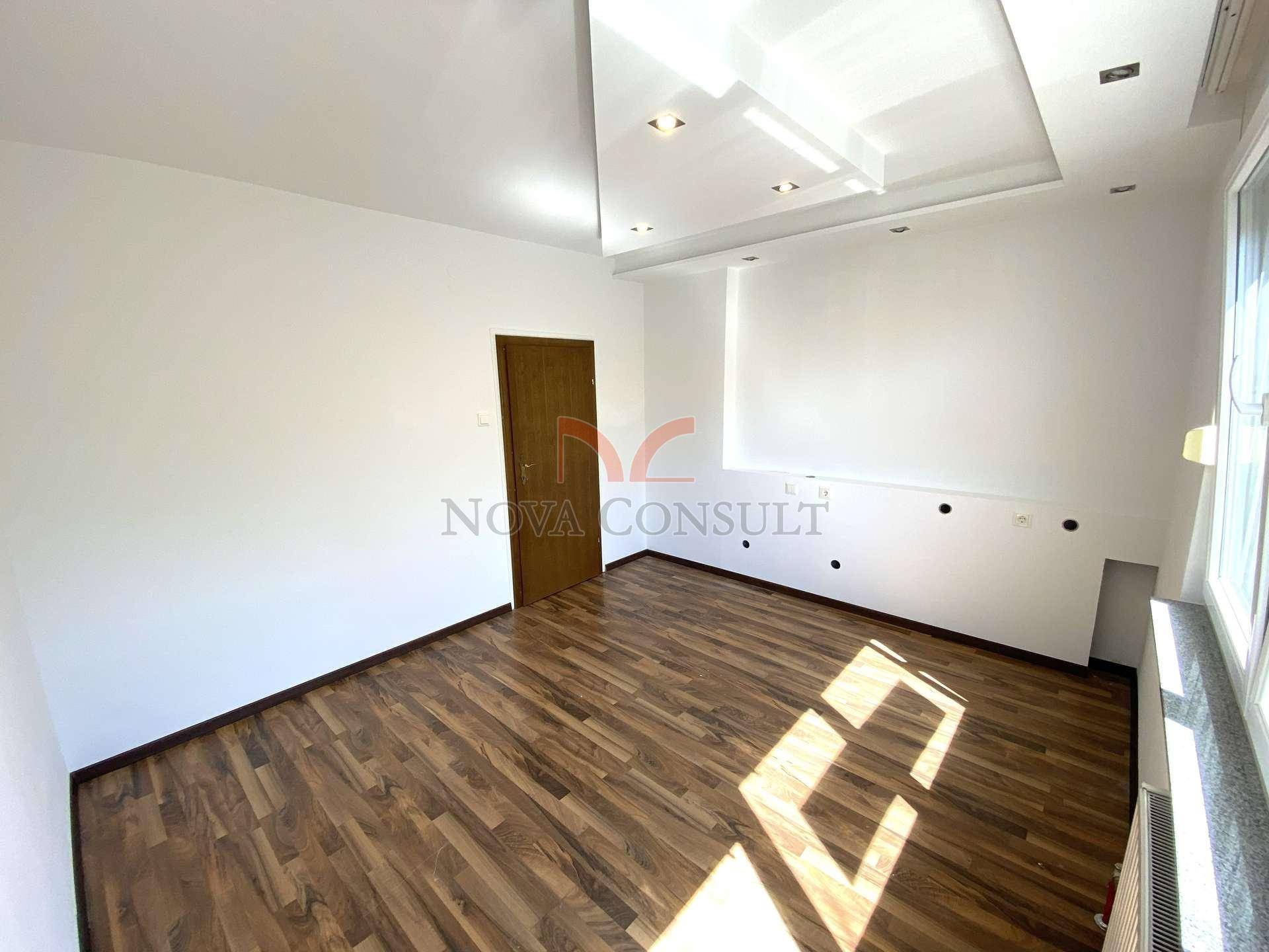 Geräumiges Schlafzimmer mit Holzboden, weiß gestrichenen Wänden und moderner Deckenbeleuchtung.