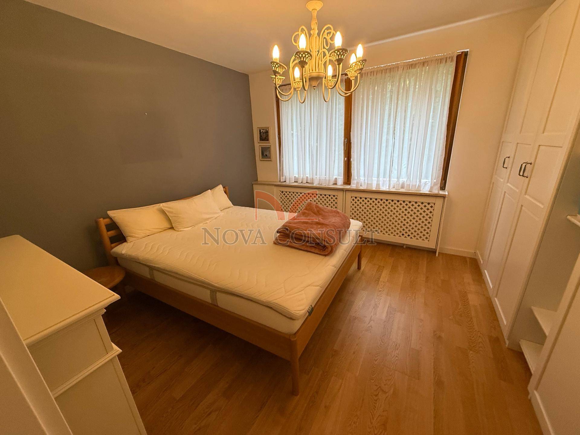 Gemütliches Schlafzimmer mit Holzbett, Parkettboden und großem Fenster, hell und einladend.