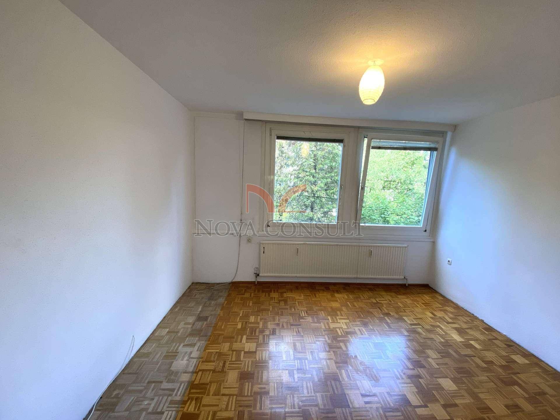 Geräumiges Schlafzimmer mit Parkettboden und großen Fenstern, die viel Tageslicht hereinlassen.