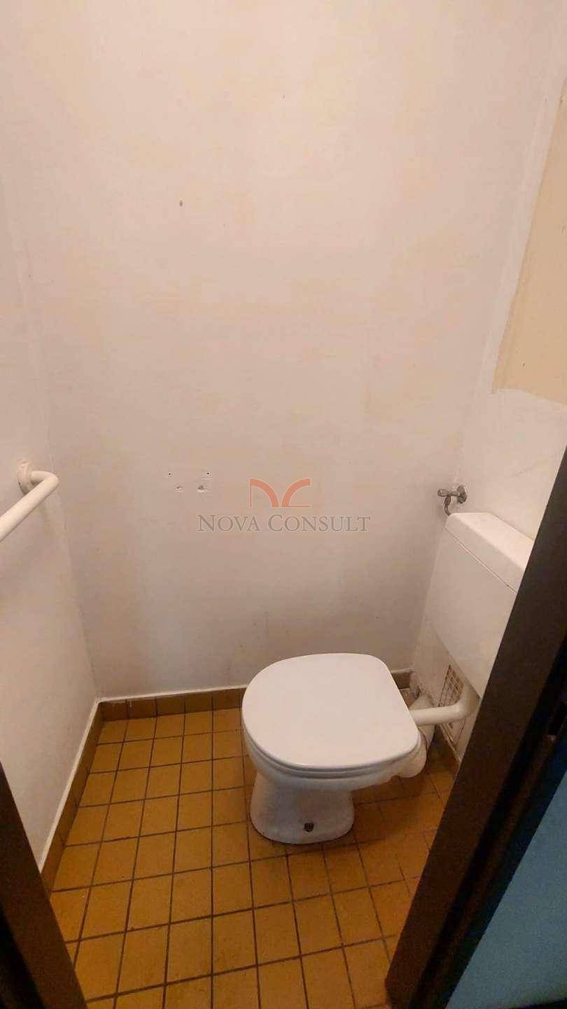 Kleines WC mit Toilette und Terrakotta-Fliesenboden, funktional und einfach gehalten.