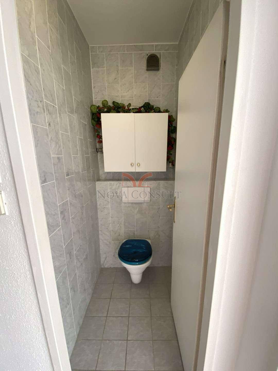 Separates WC mit Fliesenboden und Wandregal, praktisch für Gäste.