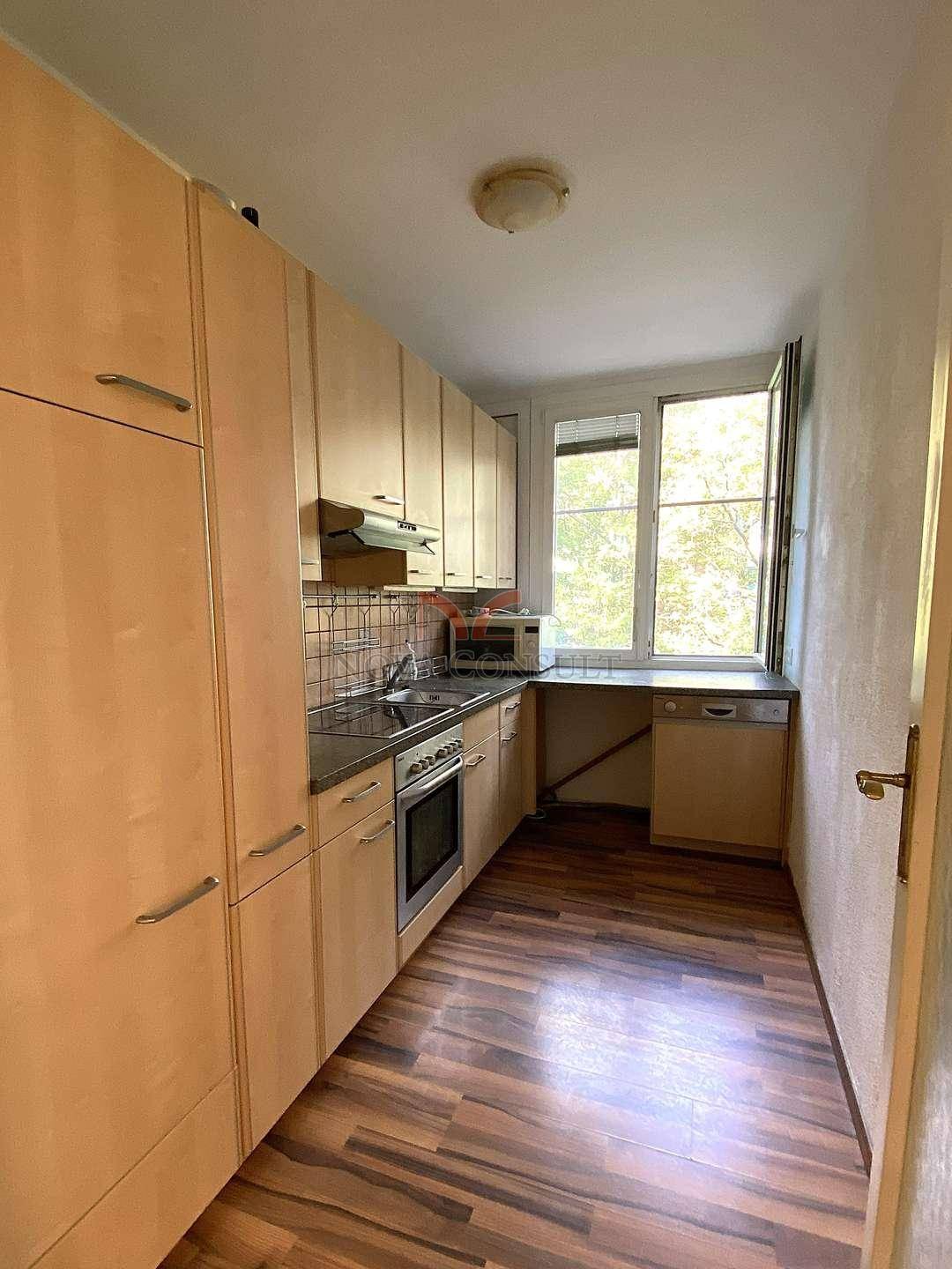 Funktionale Küche mit hellen Holzschränken, Fenster und integrierten Geräten.