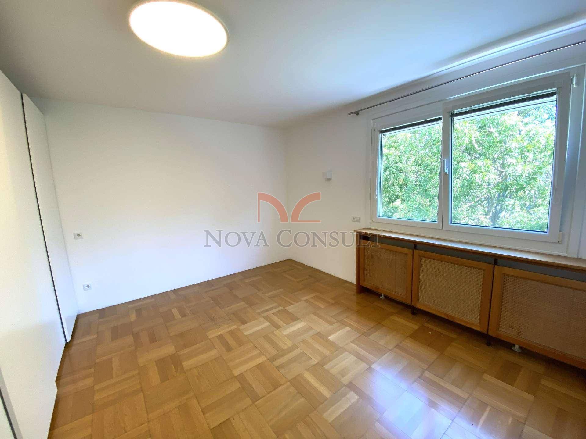Helles Schlafzimmer mit Parkettboden, Einbauschrank und großem Fenster.