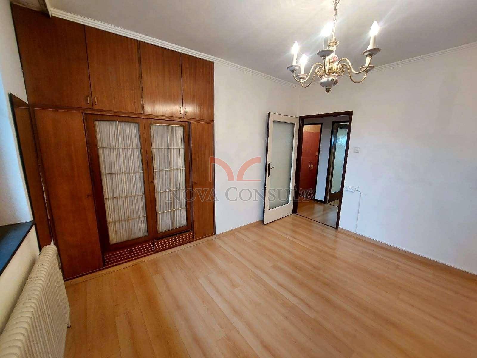 Helles Zimmer mit Laminatboden, Kronleuchter und großem Holzschrank.
