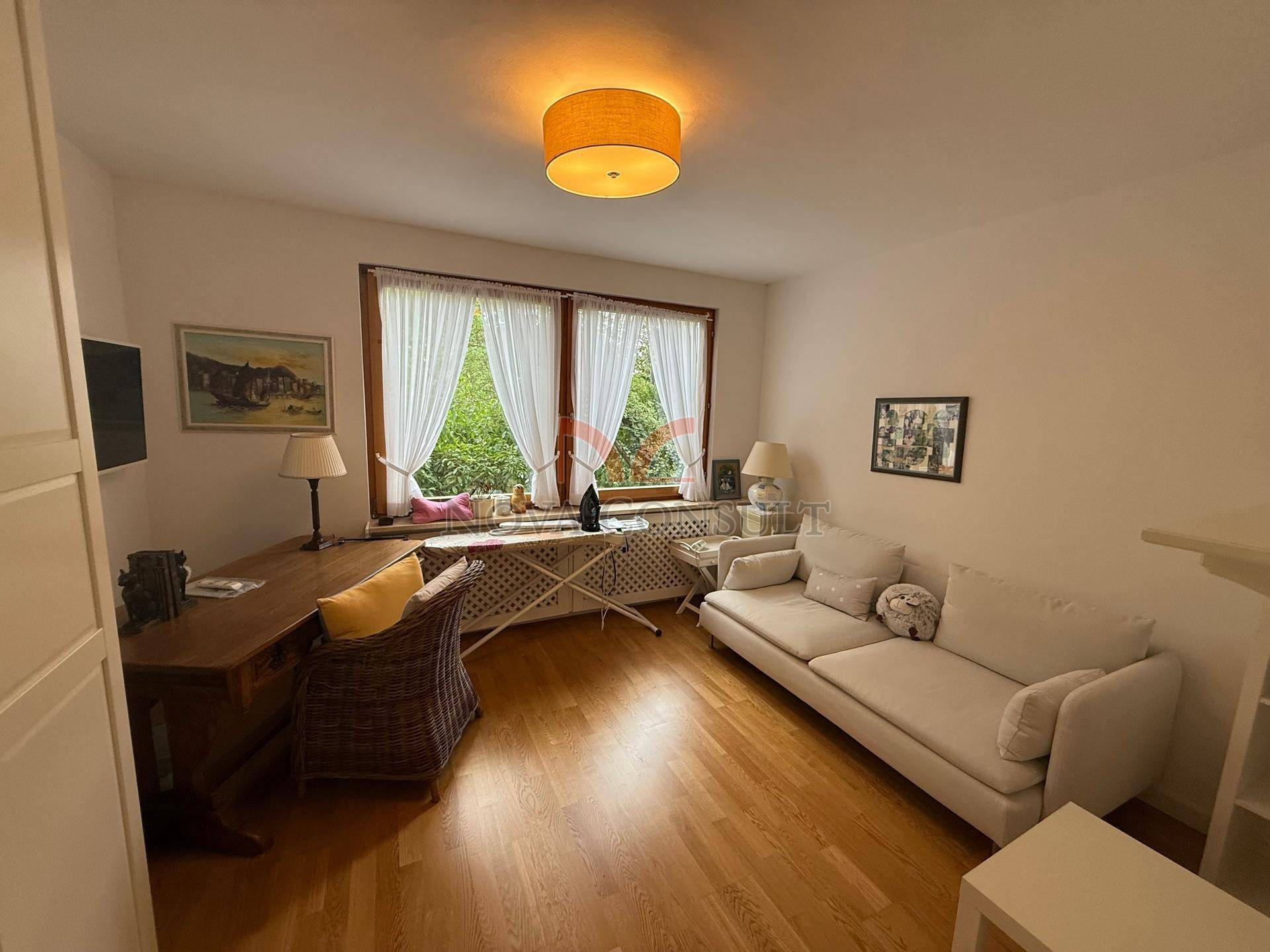 Helles Arbeitszimmer mit Parkettboden, Schreibtisch und Sofa, ideal für Home-Office.