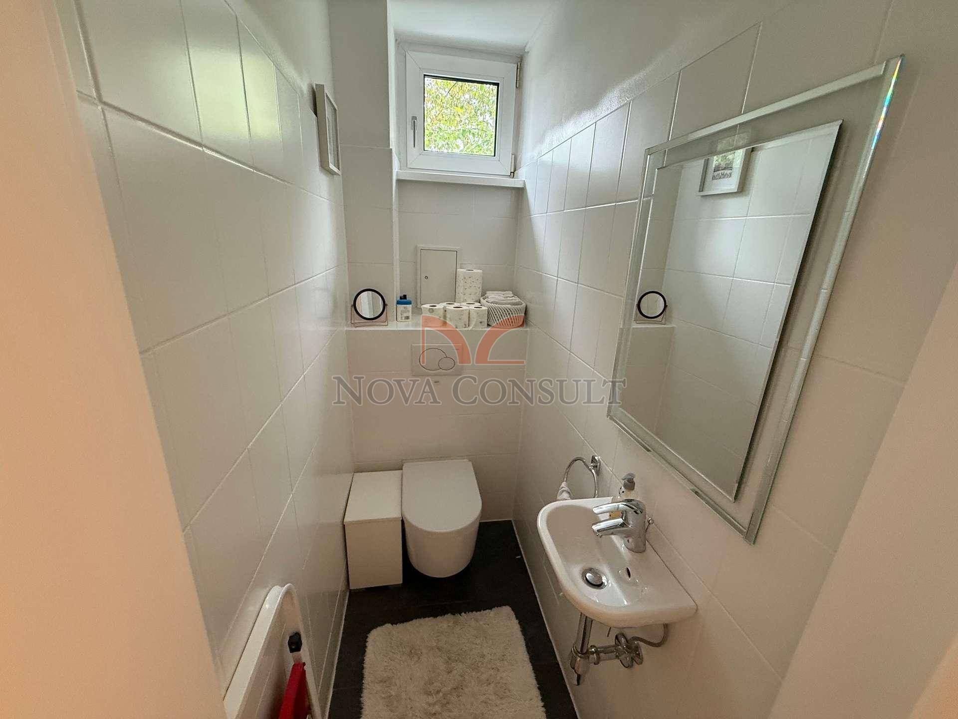 Kleines Gäste-WC mit Waschbecken, Toilette und Spiegel, hell gefliest und funktional.