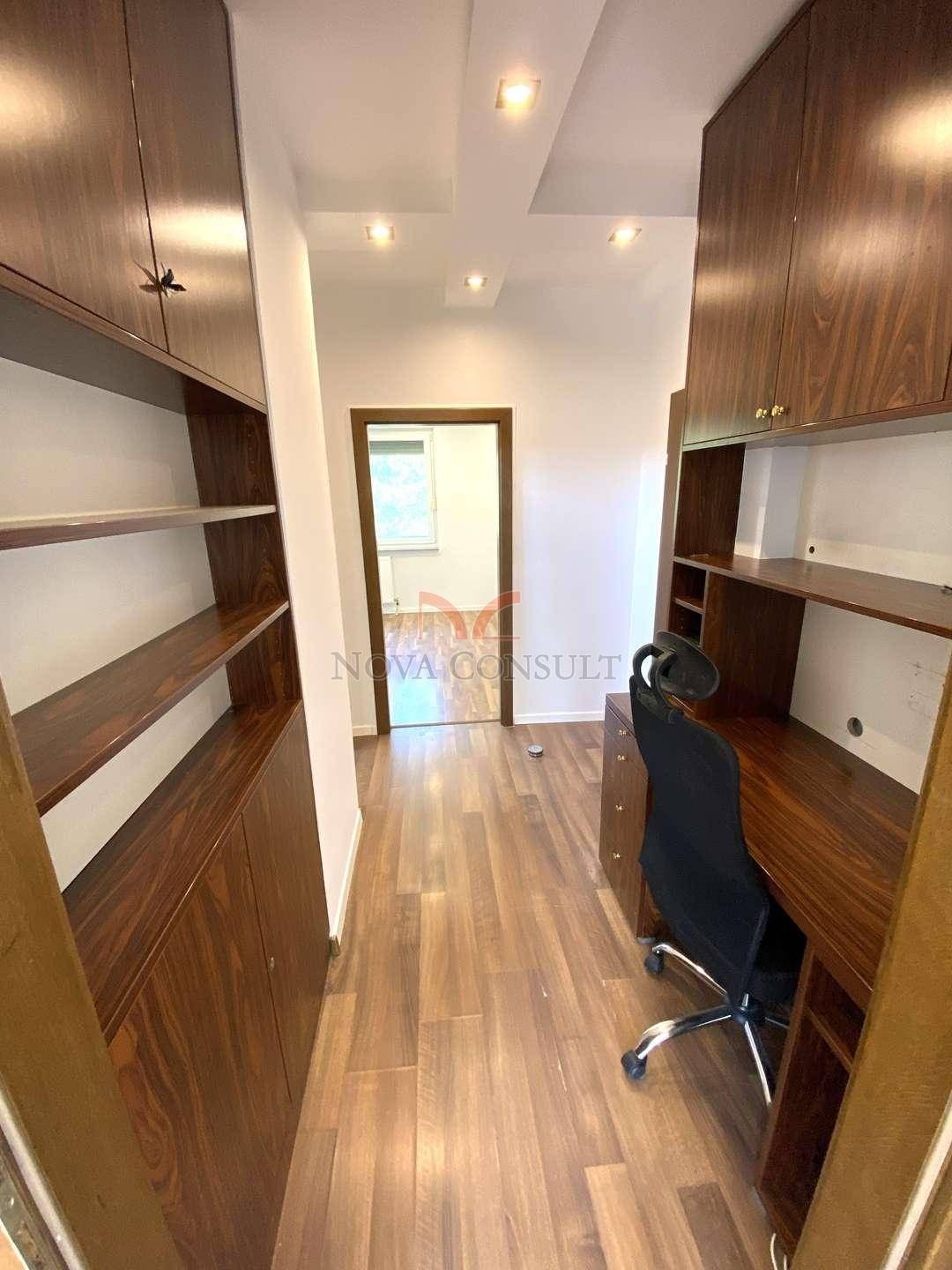 Funktionales Büro mit Holzboden, maßgefertigten Holzregalen und einem Schreibtisch.