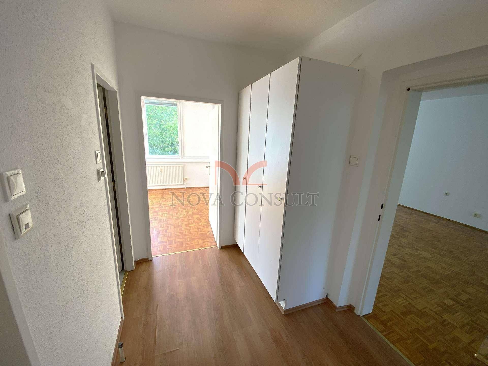 Heller Flur mit Laminatboden und weißen Einbauschränken, der zu verschiedenen Zimmern führt.