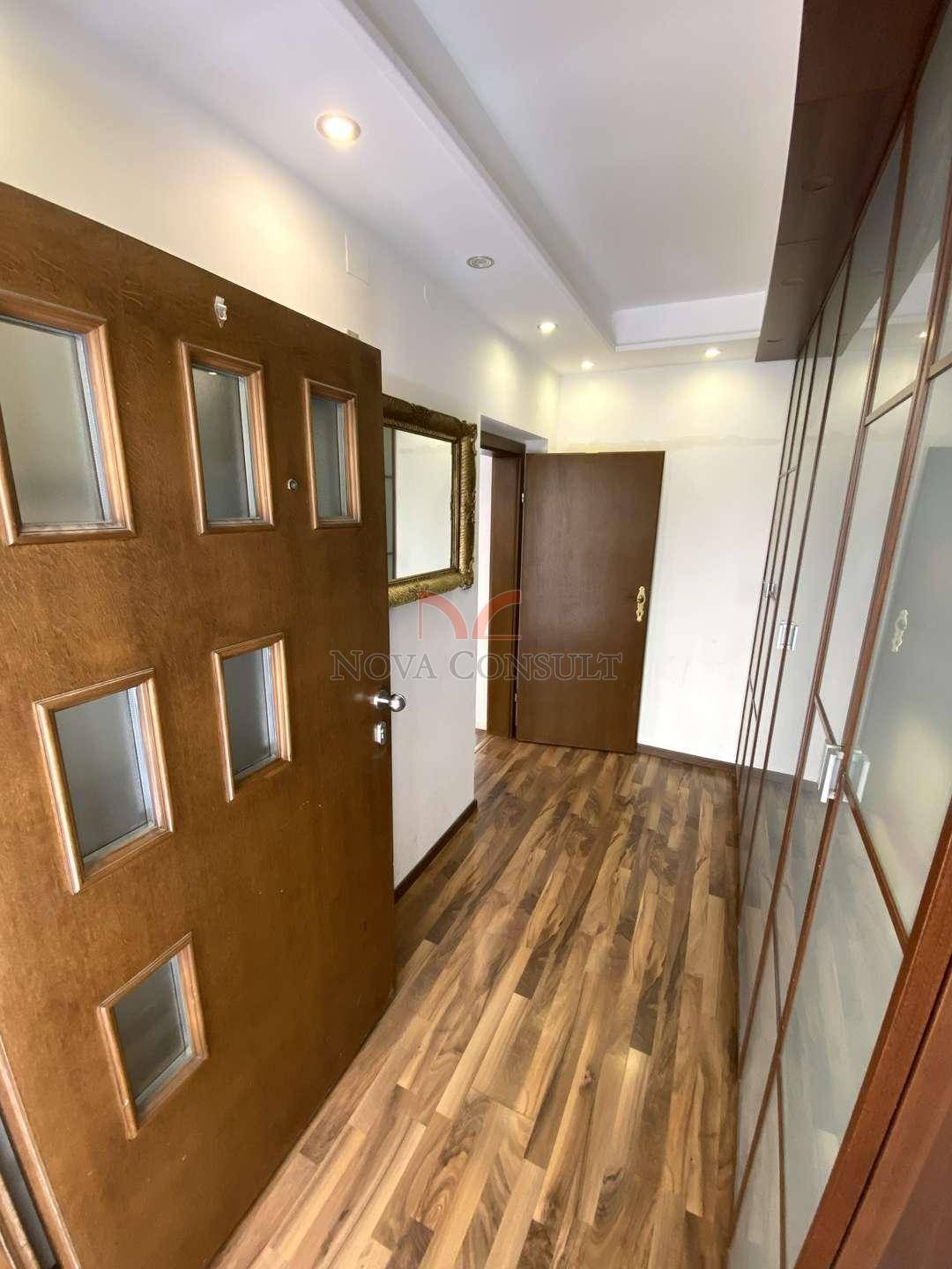 Heller Flur mit Holzboden, integrierten Schränken und einer modernen Eingangstür.
