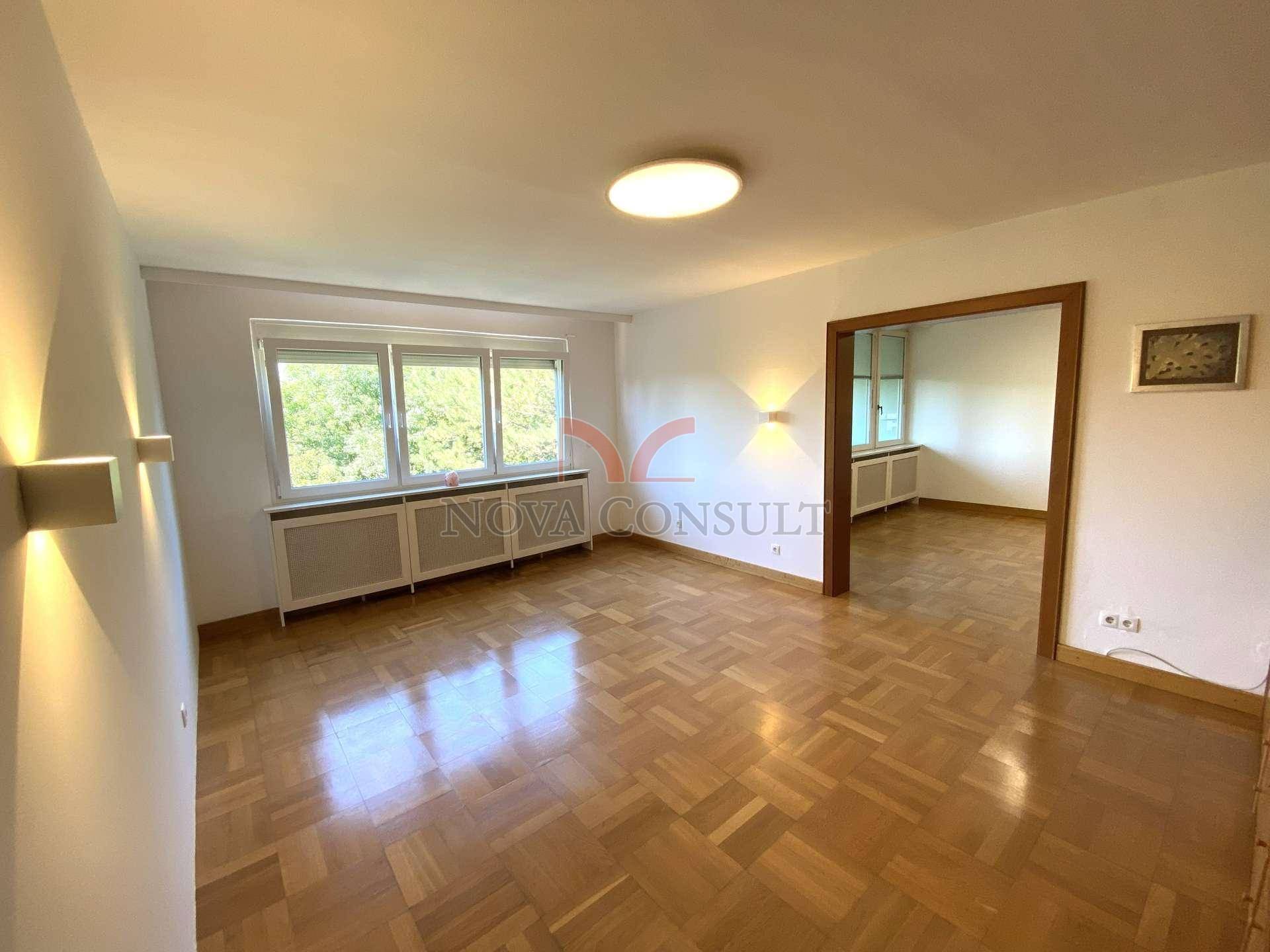 Geräumiges Wohnzimmer mit Parkettboden, großen Fenstern und viel Tageslicht.