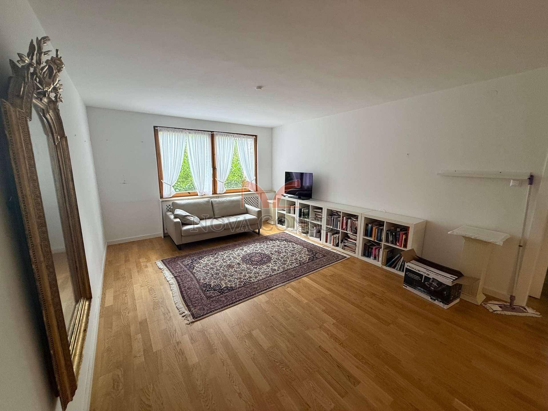 Heller Wohnbereich mit Parkettboden, Sofa und Bücherregal, ideal zum Entspannen.