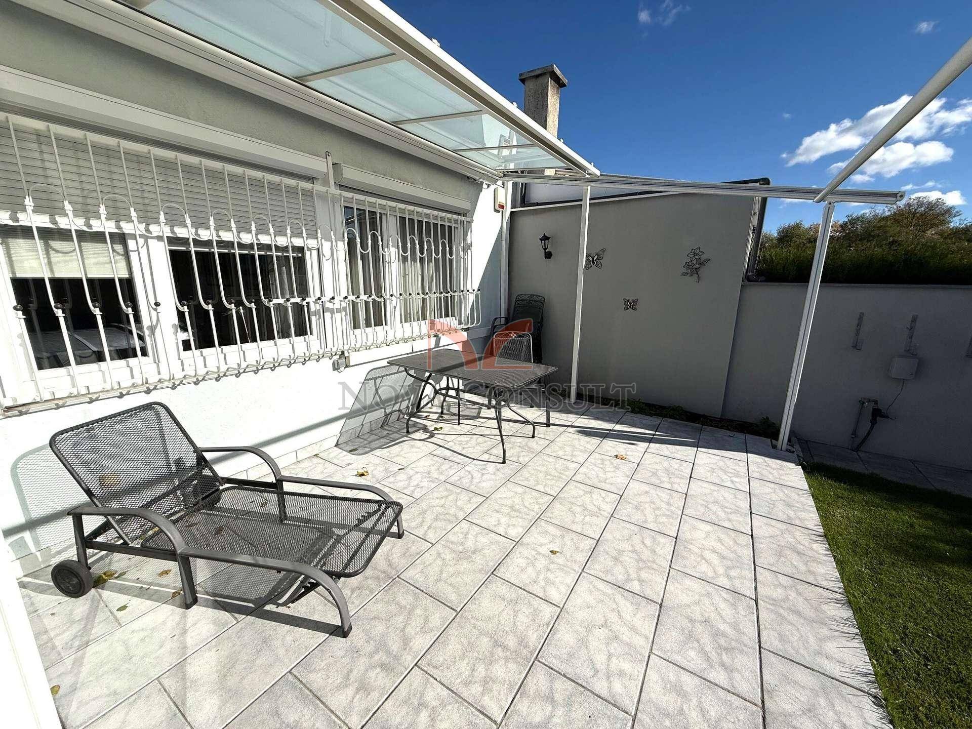Gemütliche Terrasse mit Fliesenboden und Gartenmöbeln, ideal für entspannte Stunden im Freien.