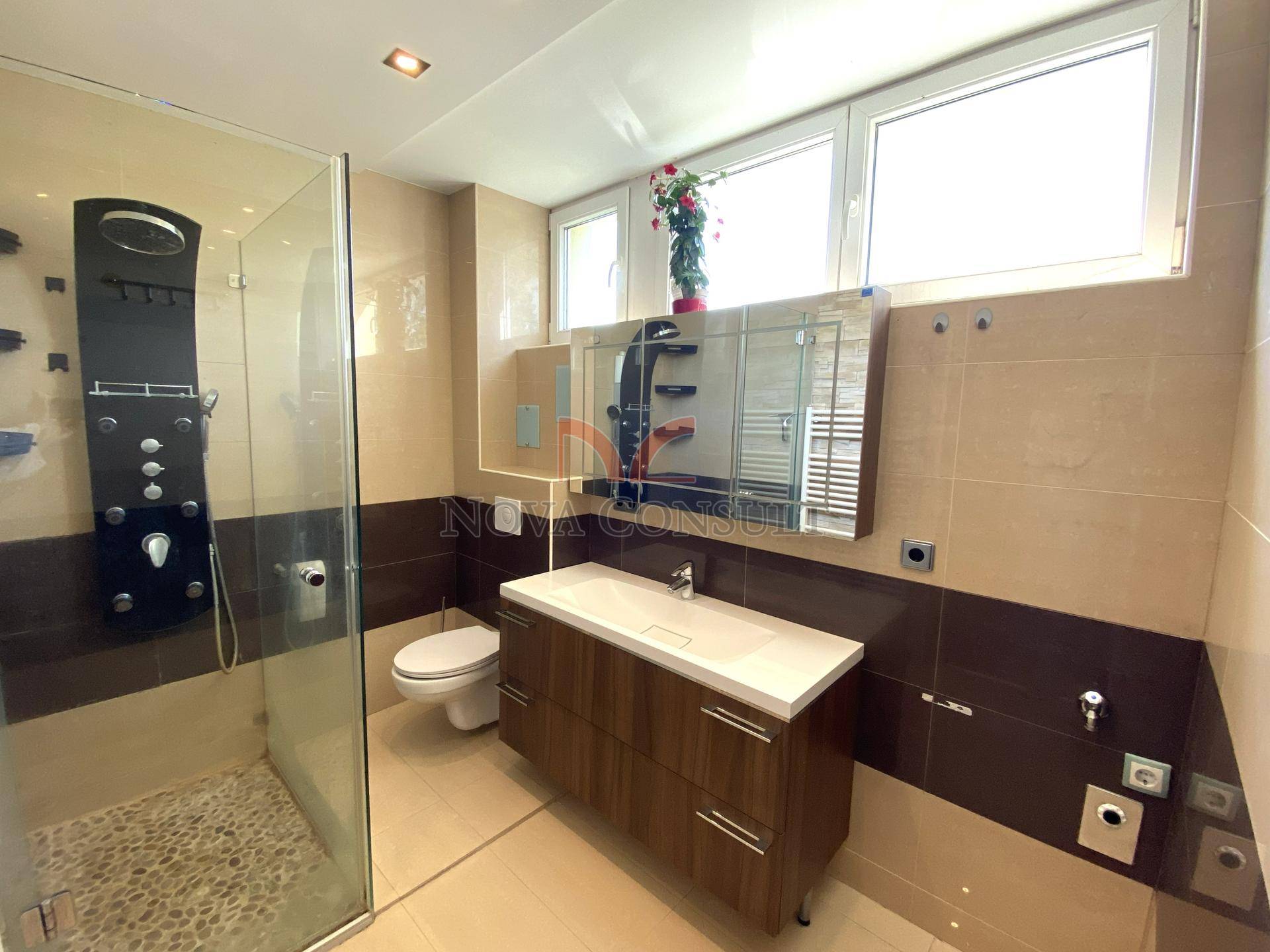 Modernes Badezimmer mit begehbarer Dusche, stilvollen Fliesen und einem Fenster.